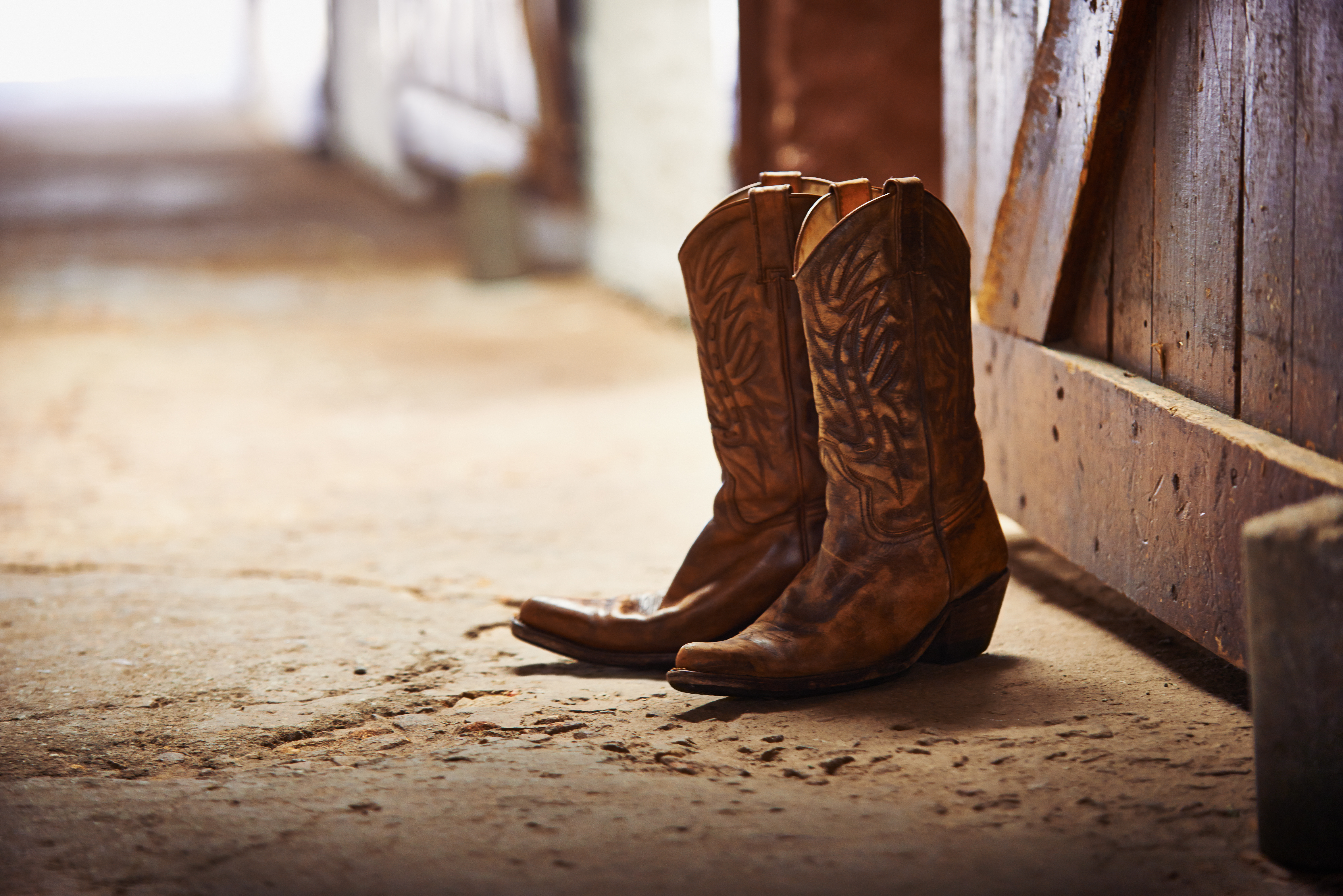 Another day done. Shot of a pair of cowboy boots in a barn.