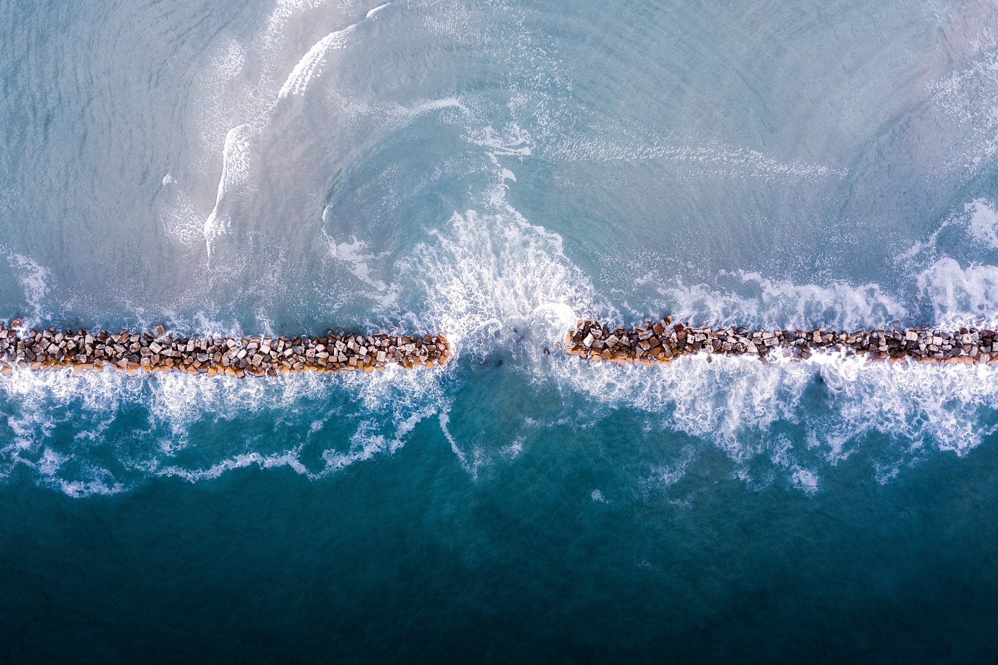 Aerial view of a blue wavy sea with a stone pier - for backgrounds
