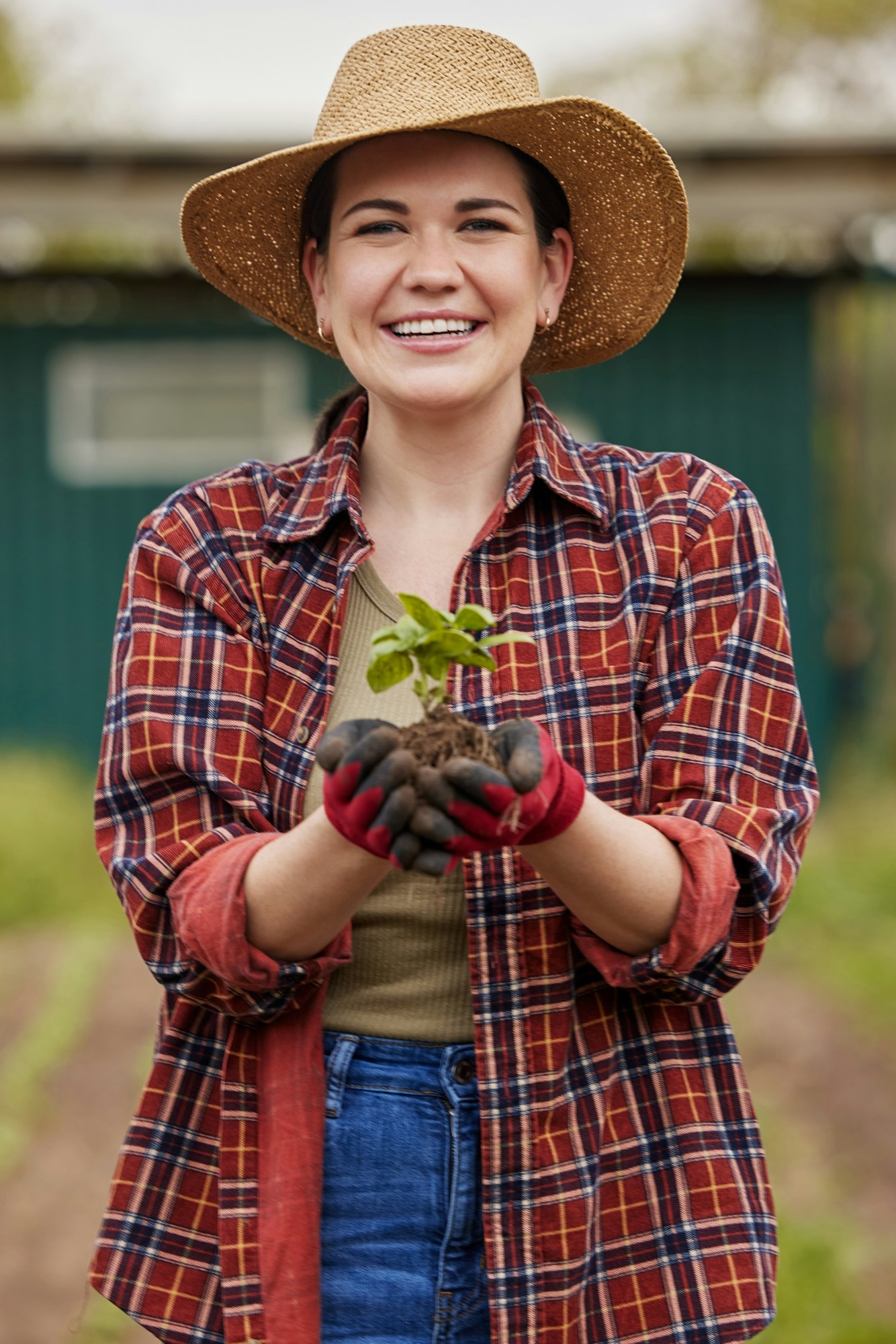 Sustainable farmer holding a plant or seedling outdoors smiling and happy about her organic farm or